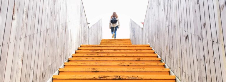 Female walking up trainline stairs with backpack