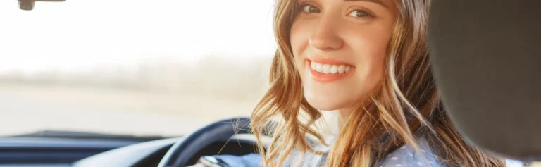 Young female smiling and driving in car